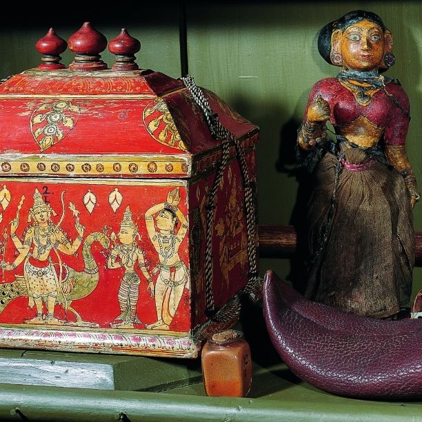 Detailansicht aus dem Indienschrank der barocken Kunst- und Naturalienkammer mit einem reich verzierten Götzenkästchen, einer ethnografischen Puppe und einem traditionellen indischen Schuh.