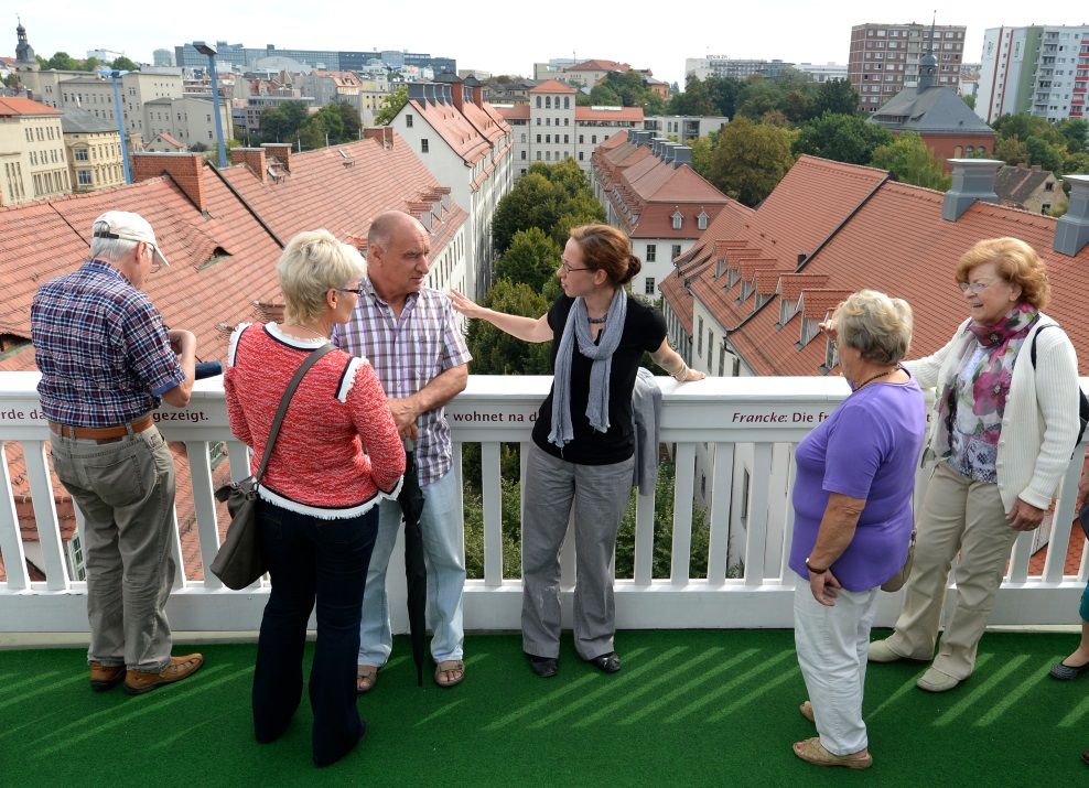A guide explains to a visitor group from the balcony of the Historical Lindenhof the many buildings of the school city of the Francke Foundations in Halle (Saale).