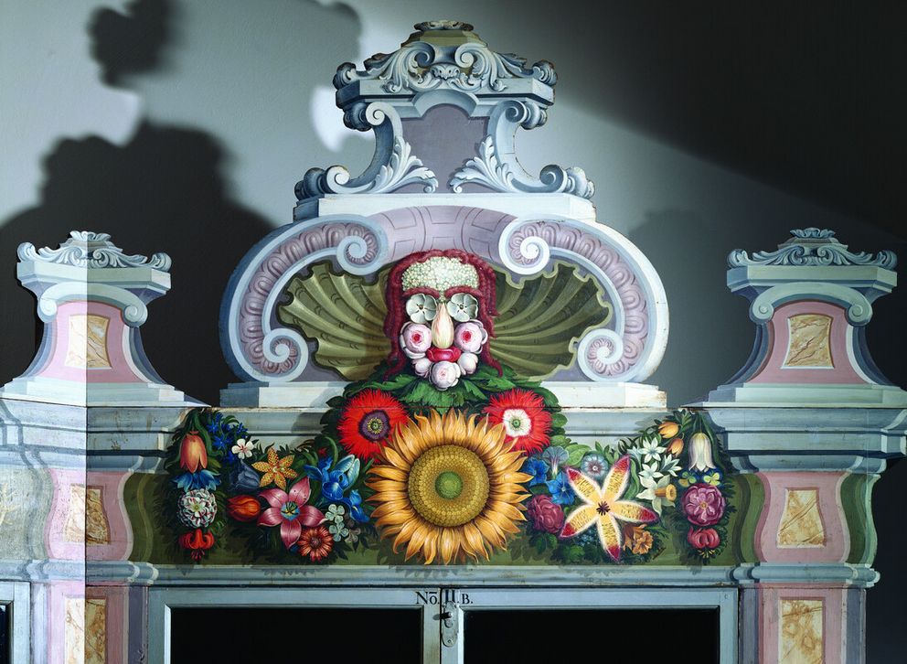Close-up of a floral face motif adorning the top of a historical plant cabinet from the Cabinet of Curiosities, inspired by the style of Giuseppe Arcimboldo.