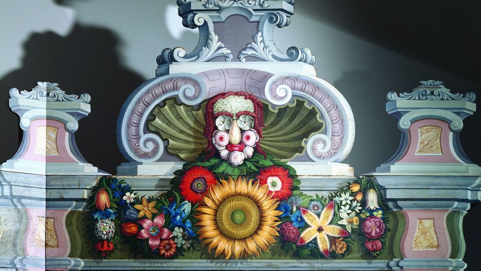Close-up of a floral face motif adorning the top of a historical plant cabinet from the Cabinet of Curiosities, inspired by the style of Giuseppe Arcimboldo.