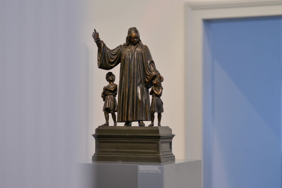 Bronzemodell des Franckedenkmals im Historischen Waisenhaus der Franckeschen Stiftungen in Halle (Saale), das den Stifter August Hermann Francke als Lehrer und Betreuer in der Mitte zeigt, umgeben von einem Mädchen und einem Jungen.