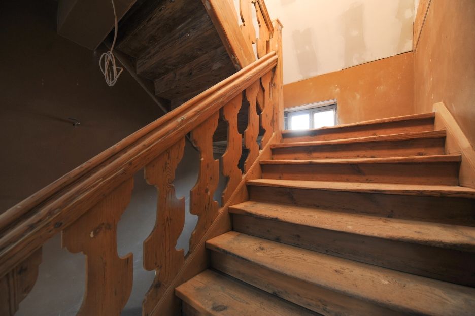 Handlauf und stark ausgetretene Stufen führen die intensive Nutzung des Druckereigebäudes vor Augen.en Holztreppe im Druckereigebäude