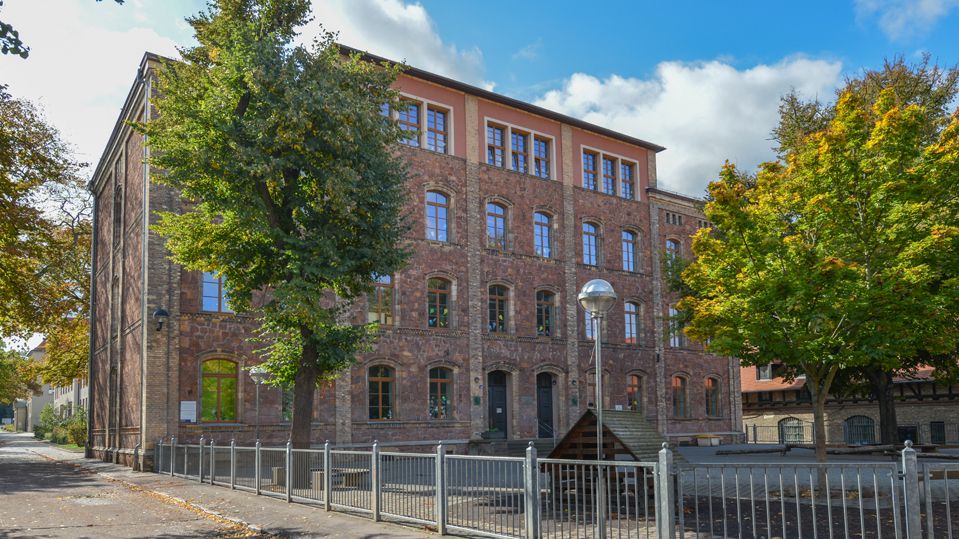 Ansicht der aus rotem Porphyr errichteten heutigen Grundschule auf dem Gelände der Franckeschen Stiftungen mit dem Schulhof.