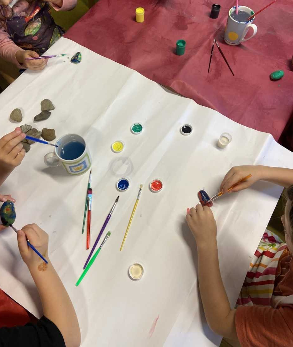Mehrere Kinder malen Steine mit Farbe an.